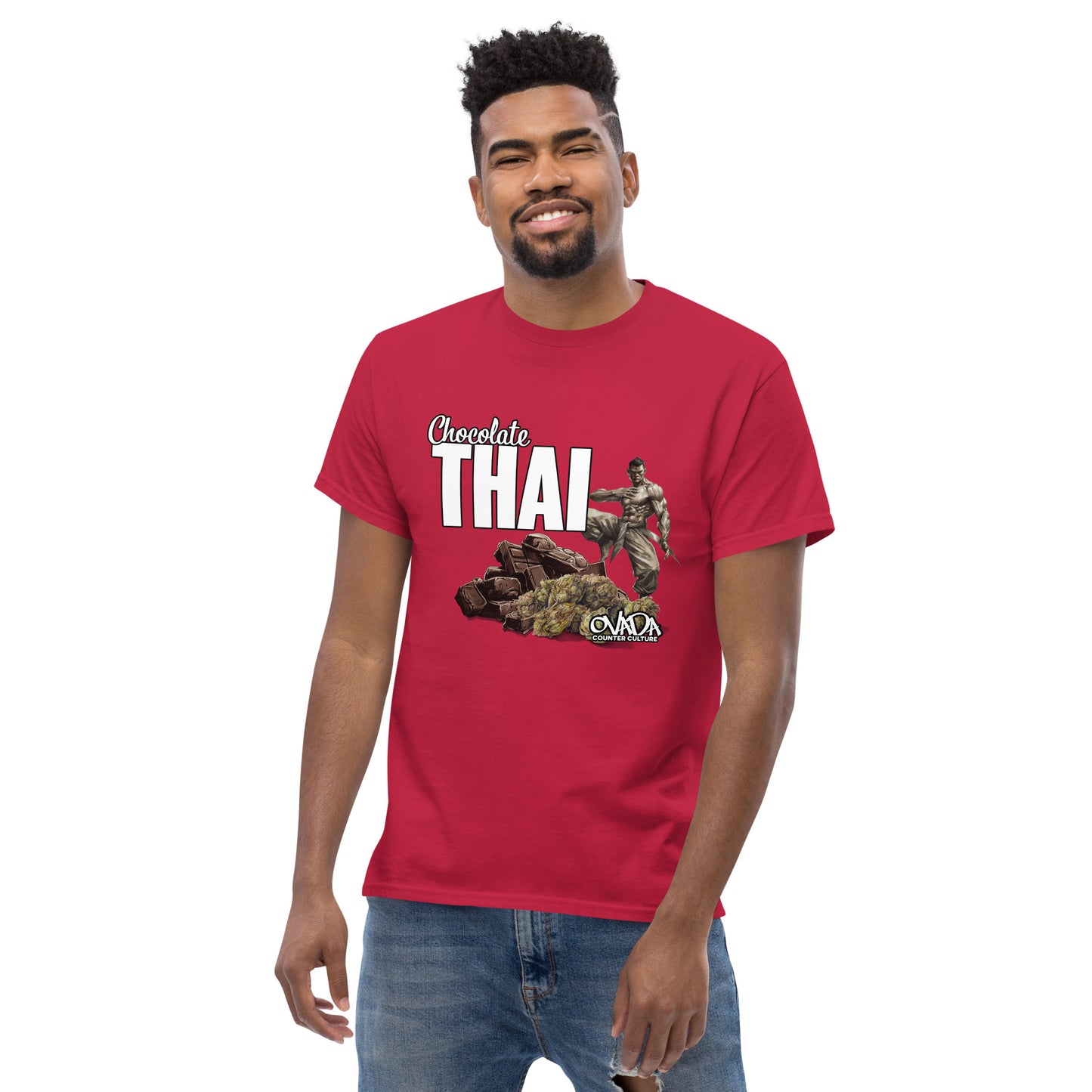 A man in a cardinal red cotton graphic t-shirt with the words Chocolate Thai. A cartoon depiction of a Muay Thai Fighter is standing on a pile of chocolates, with marijuana buds in front of it.