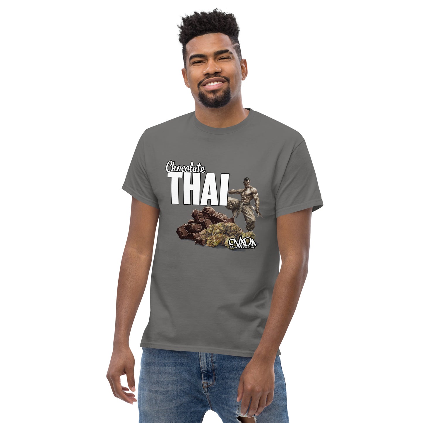 A man in a charcoal grey cotton graphic t-shirt with the words Chocolate Thai. A cartoon depiction of a Muay Thai Fighter is standing on a pile of chocolates, with marijuana buds in front of it.
