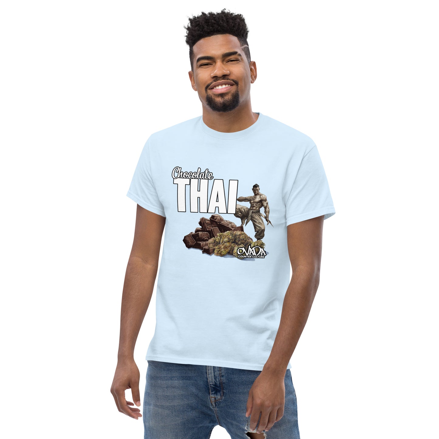 A man in a light blue cotton graphic t-shirt with the words Chocolate Thai. A cartoon depiction of a Muay Thai Fighter is standing on a pile of chocolates, with marijuana buds in front of it.