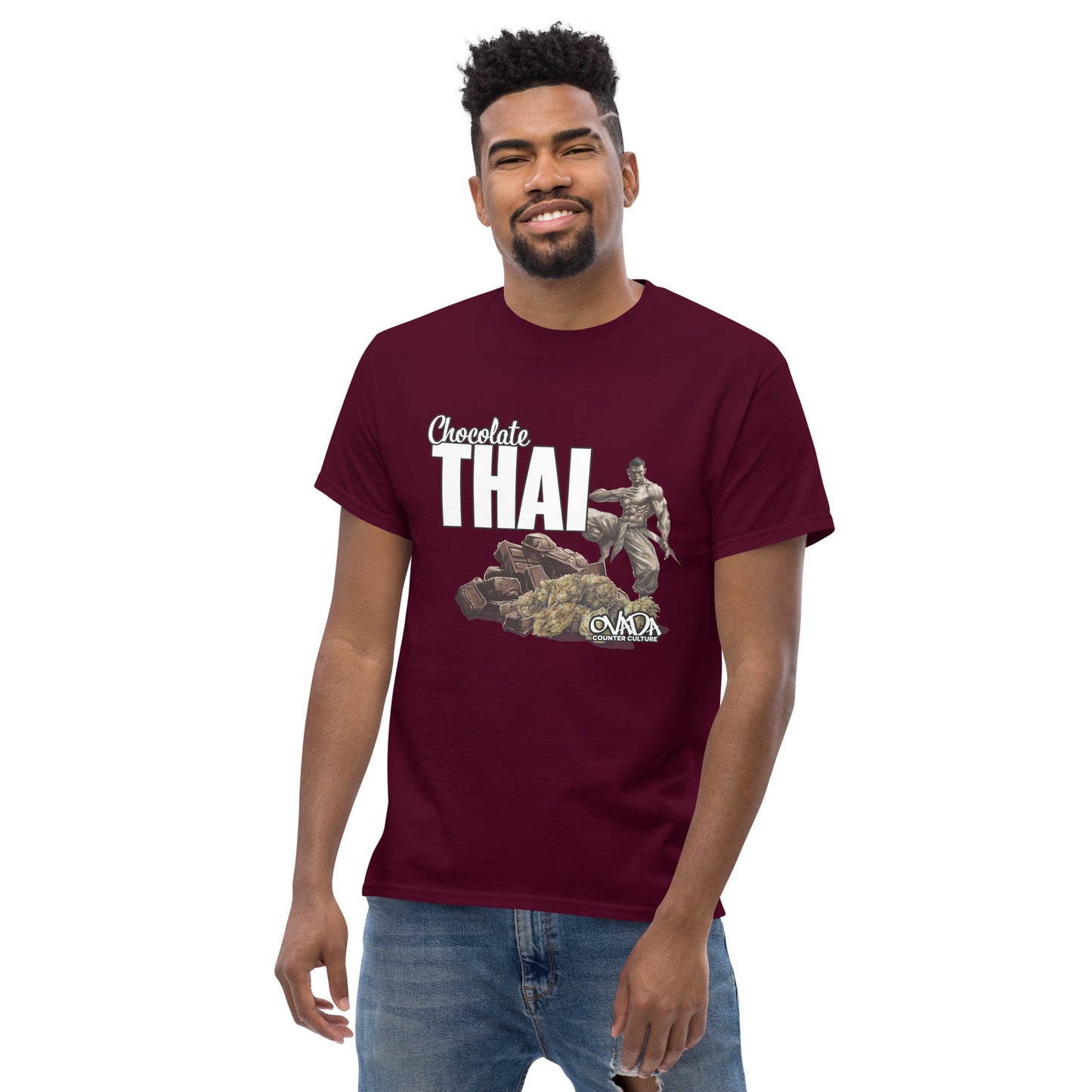 A man in a maroon cotton graphic t-shirt with the words Chocolate Thai. A cartoon depiction of a Muay Thai Fighter is standing on a pile of chocolates, with marijuana buds in front of it.