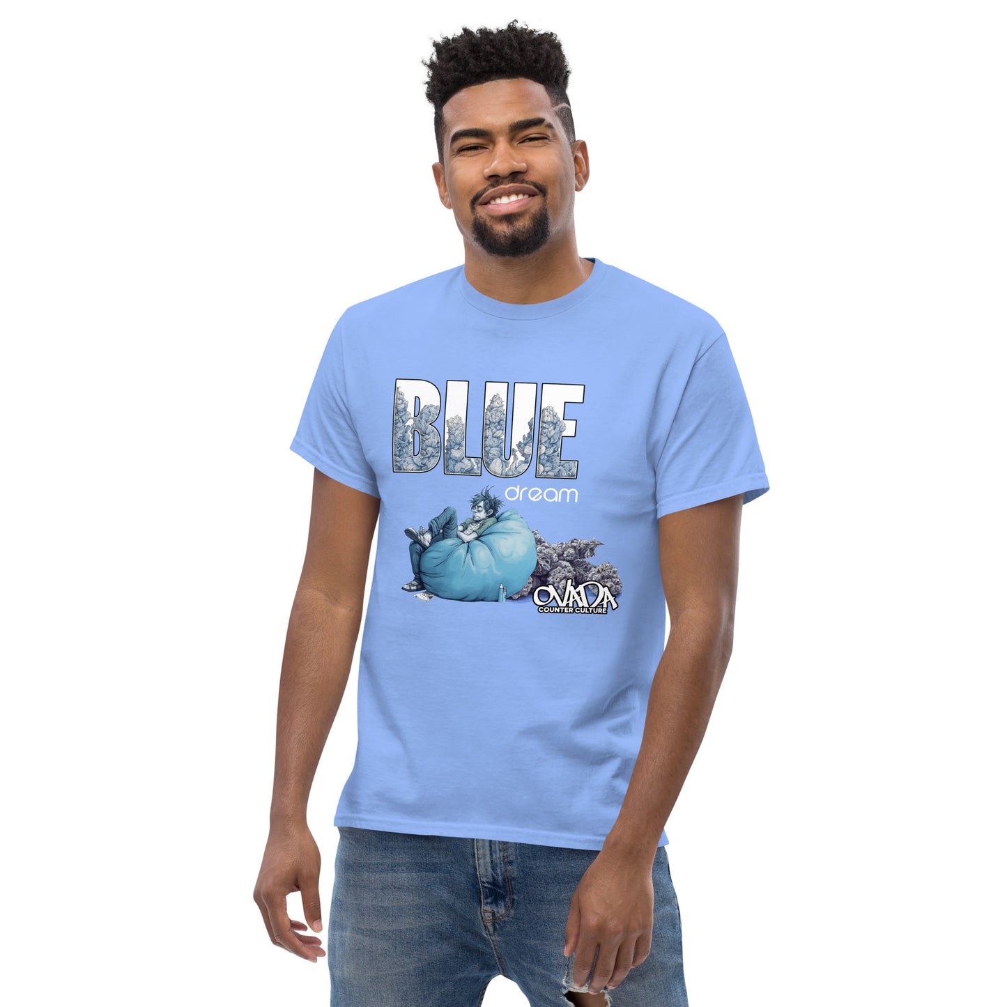 A man in a Carolina blue cotton graphic t-shirt with the words Blue Dream. A monochromatic blue cartoon depiction of a stoner passed out in a bean back with marijuana buds behind him. Weed