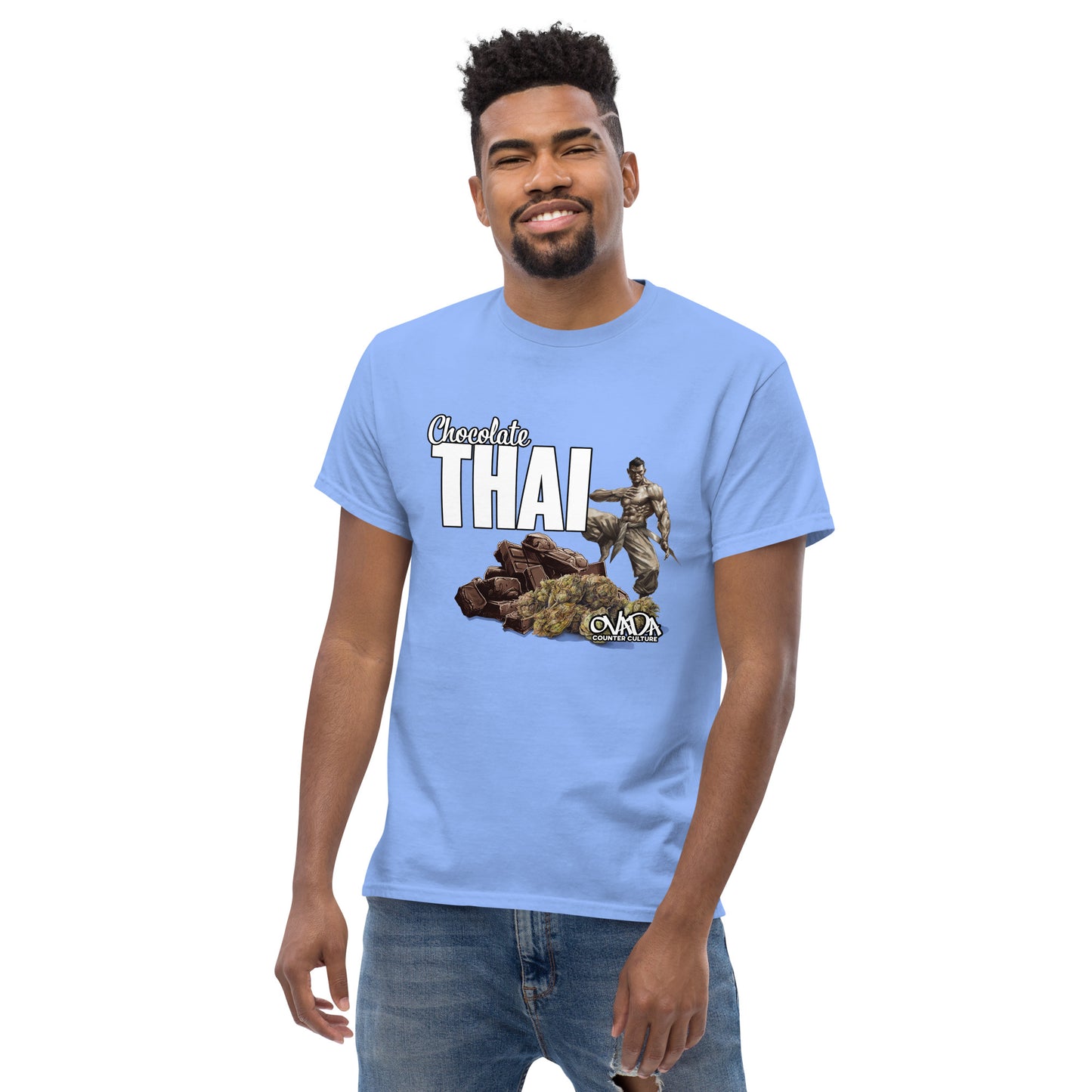 A man in a Carolina blue cotton graphic t-shirt with the words Chocolate Thai. A cartoon depiction of a Muay Thai Fighter is standing on a pile of chocolates, with marijuana buds in front of it. 