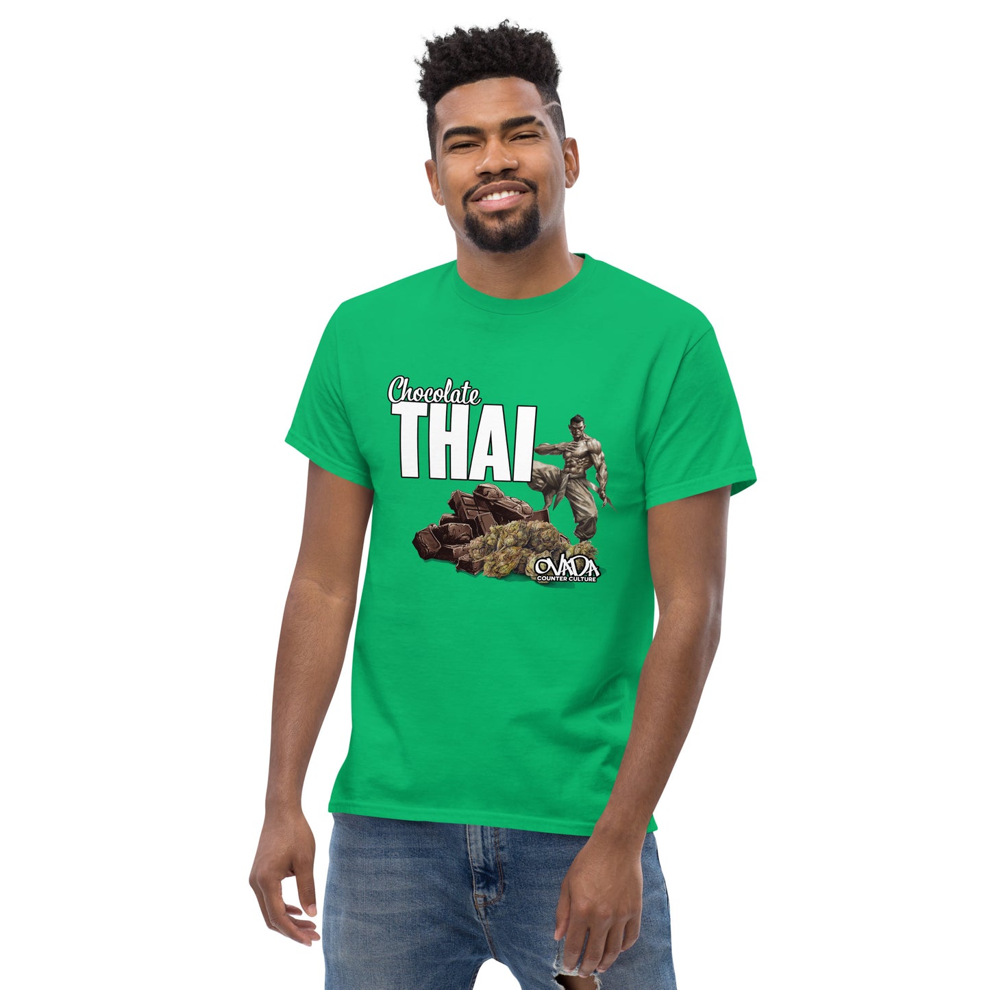 A man in a green cotton graphic t-shirt with the words Chocolate Thai. A cartoon depiction of a Muay Thai Fighter is standing on a pile of chocolates, with marijuana buds in front of it. 