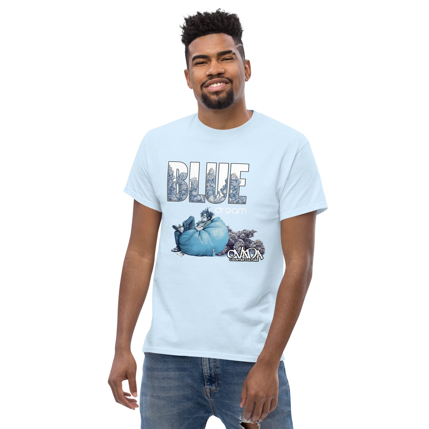 A man in a light blue cotton graphic t-shirt with the words Blue Dream. A monochromatic blue cartoon depiction of a stoner passed out in a bean back with marijuana buds behind him. Weed