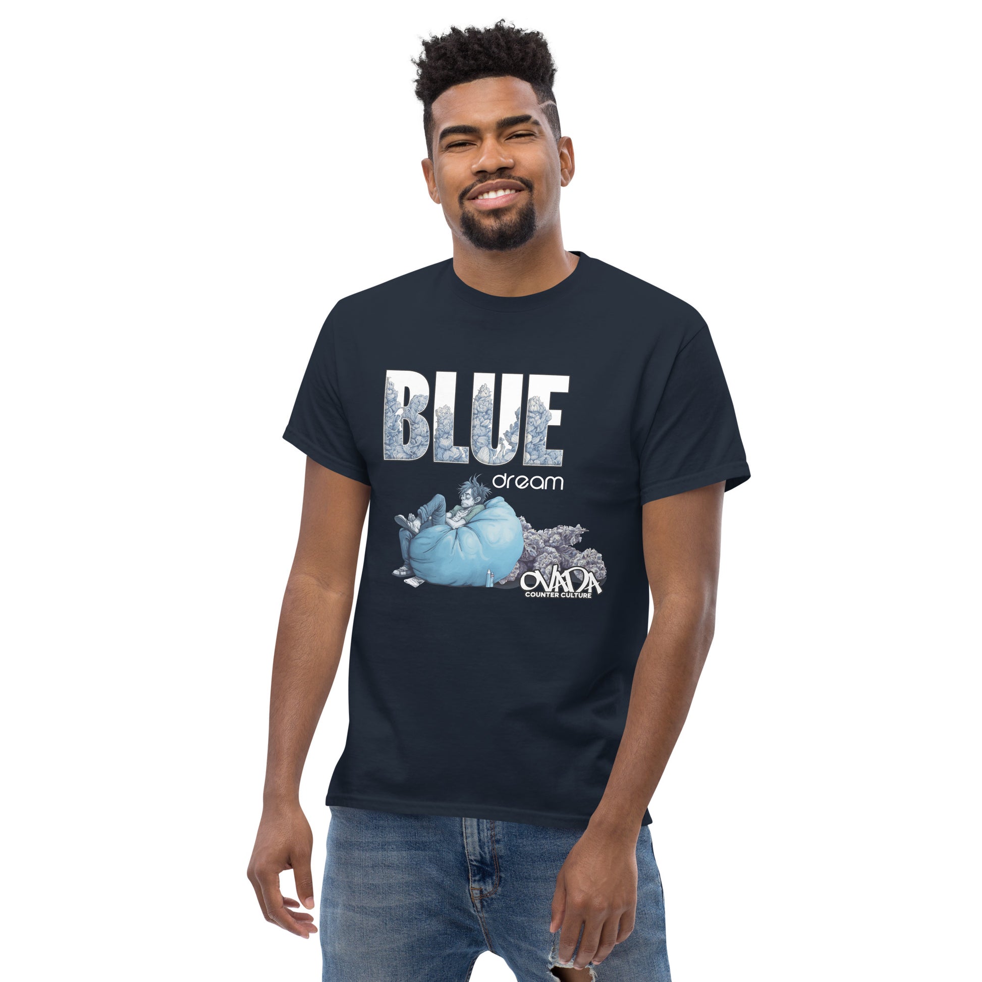 A man in a navy blue cotton graphic t-shirt with the words Blue Dream. A monochromatic blue cartoon depiction of a stoner passed out in a bean back with marijuana buds behind him. Weed