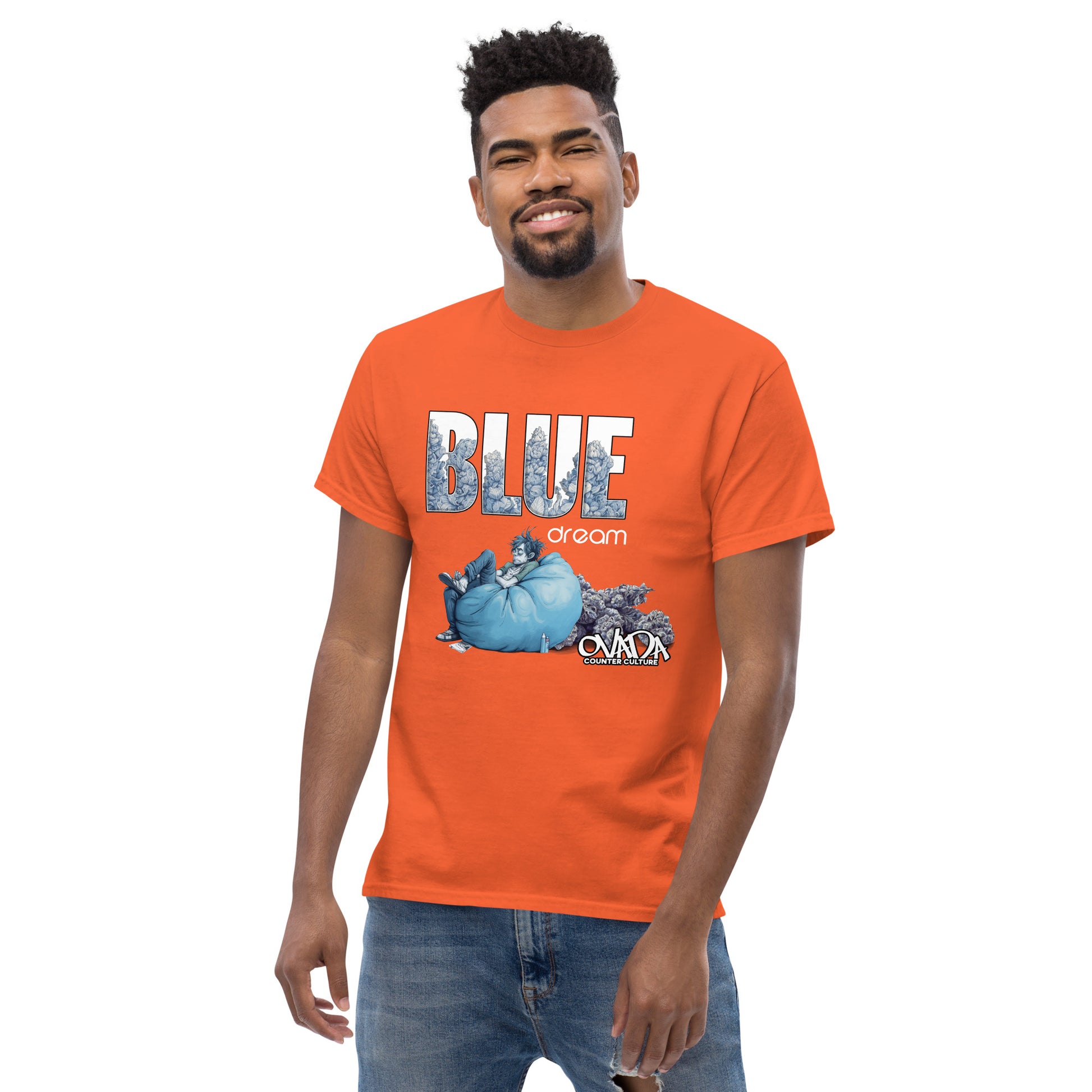 A man in an orange cotton graphic t-shirt with the words Blue Dream. A monochromatic blue cartoon depiction of a stoner passed out in a bean back with marijuana buds behind him. Weed