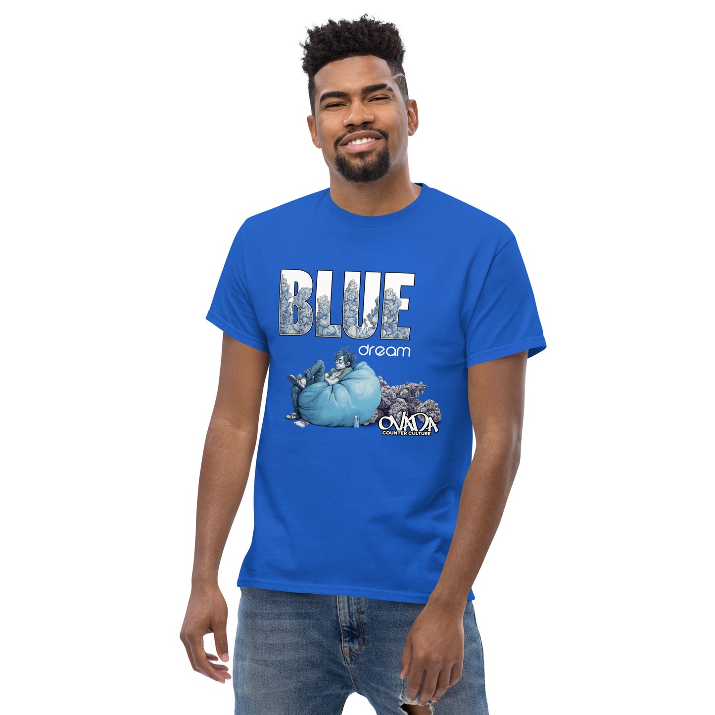 A man in a royal blue cotton graphic t-shirt with the words Blue Dream. A monochromatic blue cartoon depiction of a stoner passed out in a bean back with marijuana buds behind him. Weed