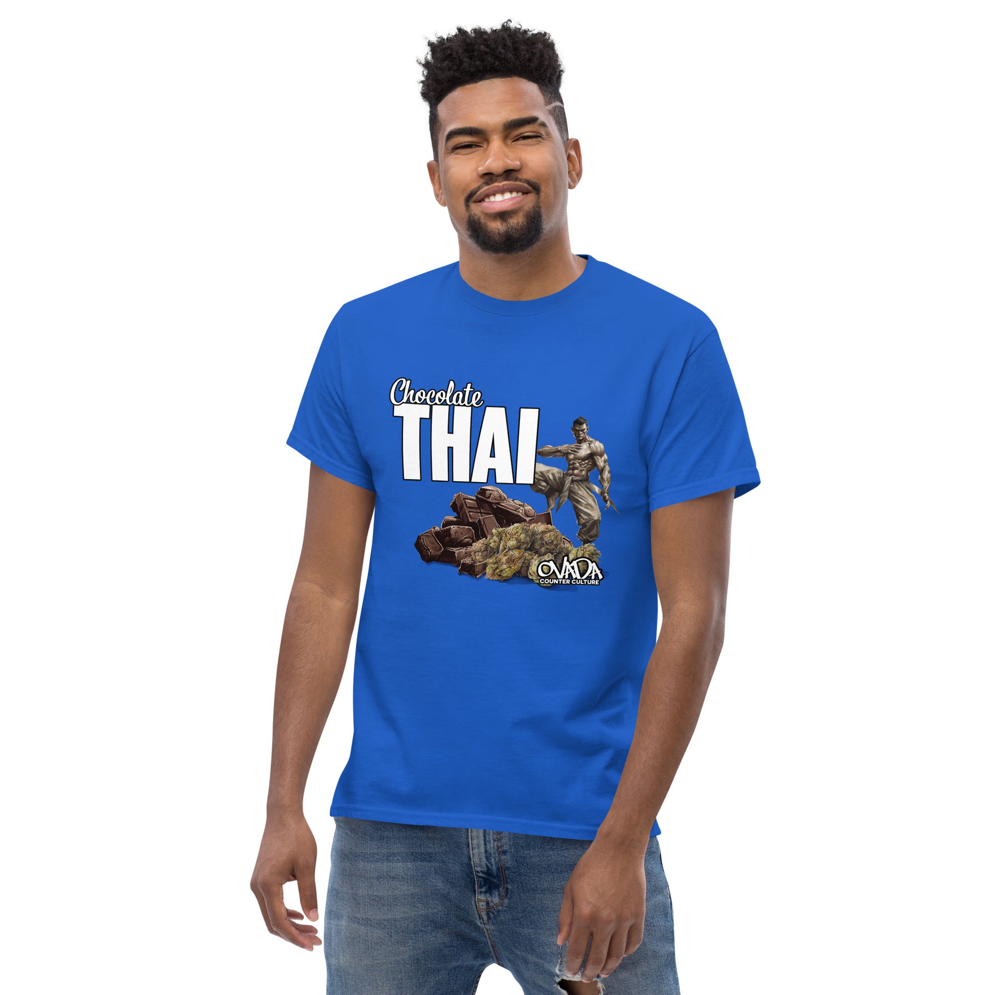 A man in a royal blue cotton graphic t-shirt with the words Chocolate Thai. A cartoon depiction of a Muay Thai Fighter is standing on a pile of chocolates, with marijuana buds in front of it. 